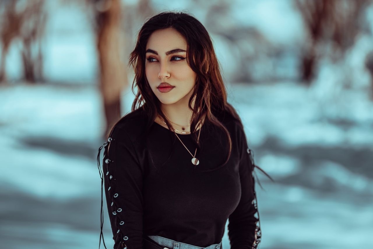 Portrait of a young woman in a snowy outdoor setting, exuding elegance and style.